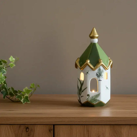 Decorative lantern with green roof and gold accents on a wooden surface.