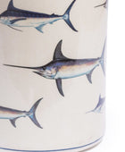 Close-up of a cylindrical container or vase with an off-white background and a repeating printed pattern of blue and gray marlin fish.