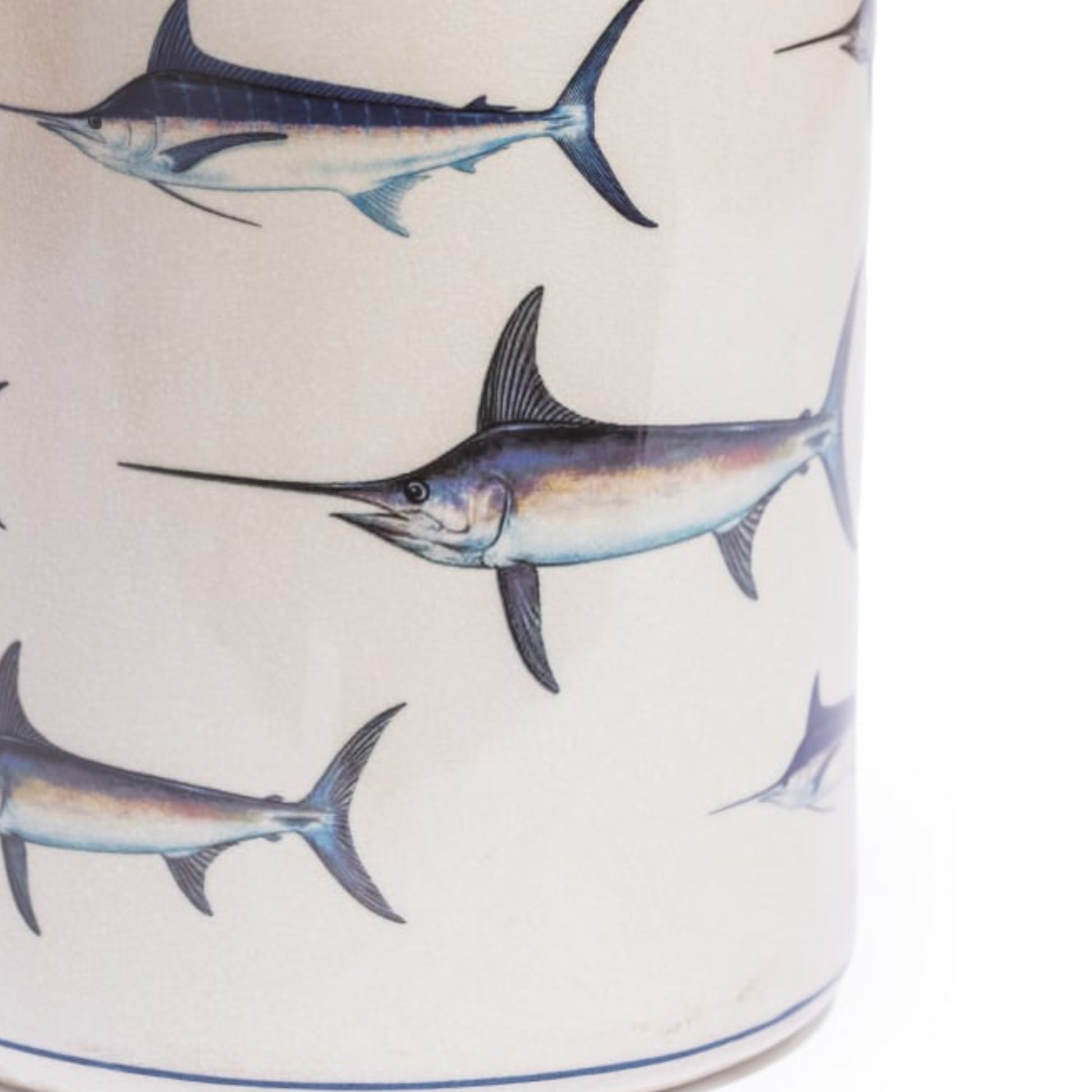Close-up of a cylindrical container or vase with an off-white background and a repeating printed pattern of blue and gray marlin fish.