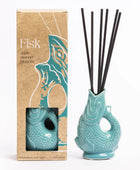 A reed diffuser set with a turquoise fish-shaped ceramic diffuser vase containing black reeds, shown next to its kraft paper packaging box labeled 'Fisk' on a white background.