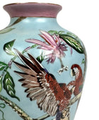 Ceramic vase with parrot and flower design on a light blue background