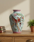Decorative vase with bird and floral design on a wooden surface