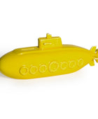 A bright yellow toy submarine with embossed details, including circular portholes and a conning tower, shown on a plain white background.
