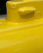 Close-up of a glossy bright yellow object, showing part of a raised molded section with a small protruding tab and embossed details.