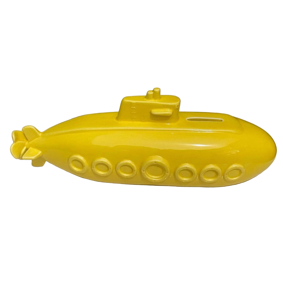 A bright yellow submarine-shaped decorative object, possibly a pig bank or money box, displayed on a light marble surface with potted plants in the background.
