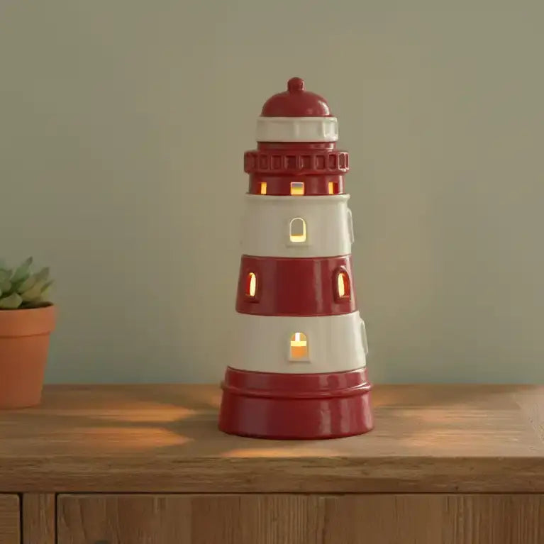 Red and white lighthouse-shaped lamp on a wooden surface with a plant in the background.