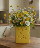 Yellow cheese-shaped vase with flowers on a kitchen counter