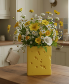 Yellow vase with flowers on a kitchen counter