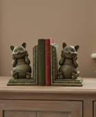 A pair of cat-shaped bookends holding a set of three vintage-style books on a wooden console table in a room setting.