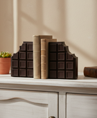 Decorative books shaped like chocolate bars on a wooden surface with a plant in the background.