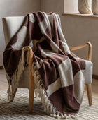 Brown and beige checkered blanket draped over a wooden chair in a room with neutral decor.