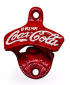 A red cast iron bottle opener designed as a Coca-Cola bottle opener, featuring the white embossed Coca-Cola script and 'DRINK' text on a white background.