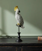 Decorative parrot sculpture on a stand against a green wall