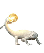 White chameleon-shaped lamp with a lit bulb on a dark background