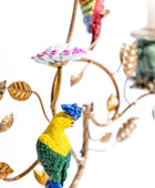 Colorful parrot figurine on a decorative branch with leaves and flowers.