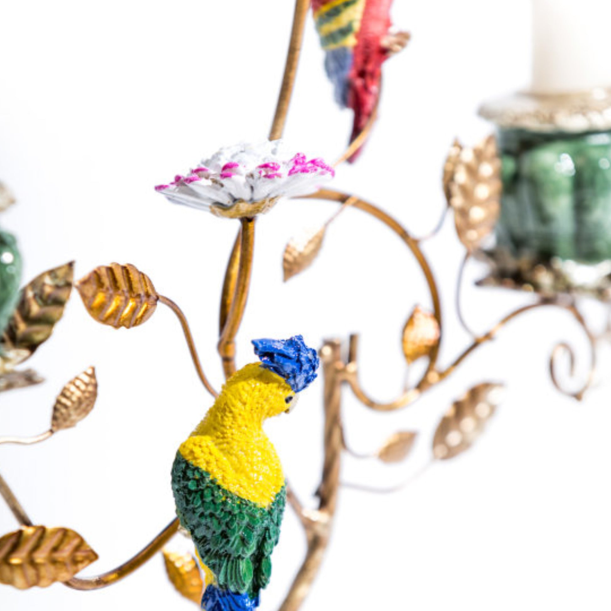 Colorful parrot figurine on a decorative branch with leaves and flowers.