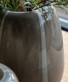 Gray vase with a plant on a wooden surface