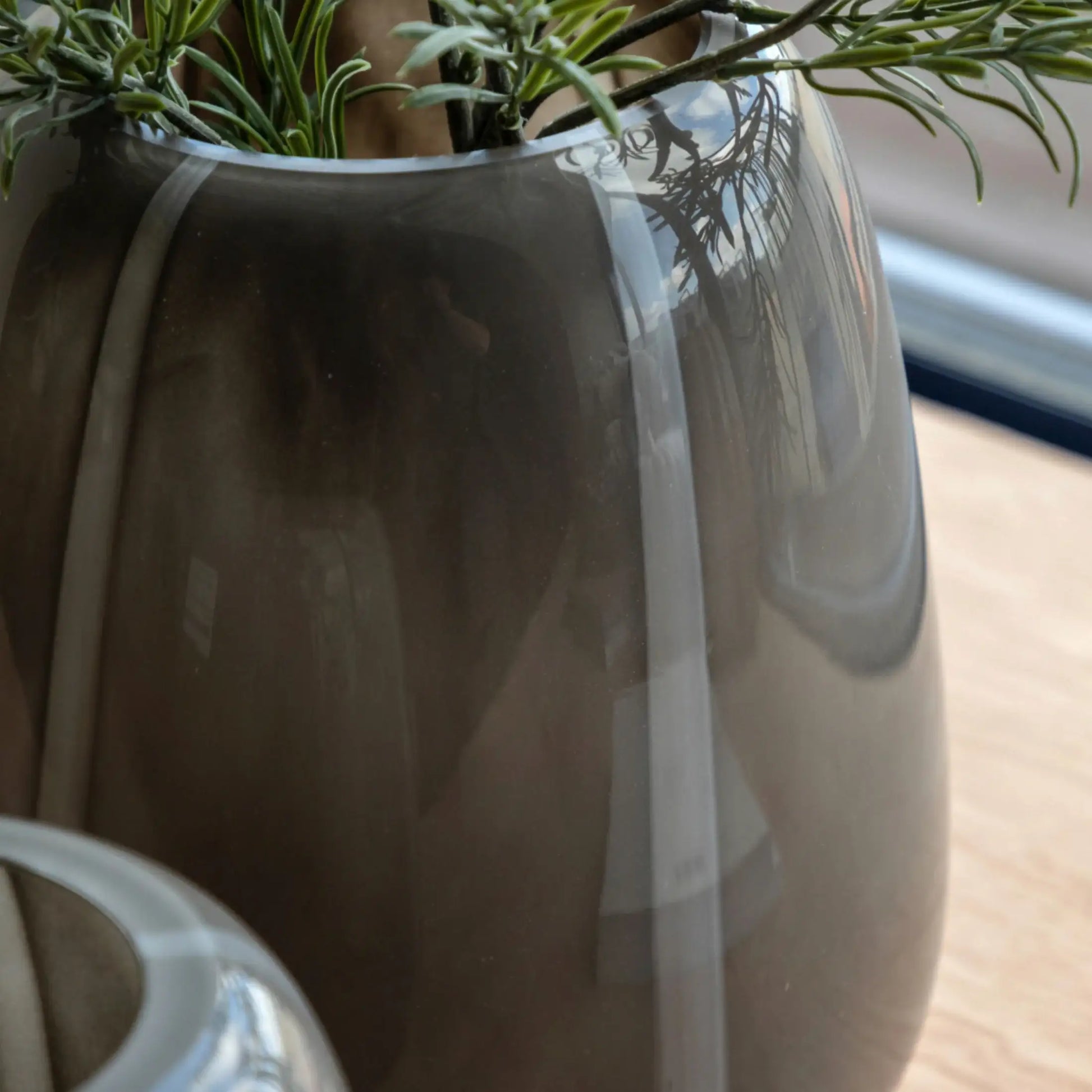 Gray vase with a plant on a wooden surface