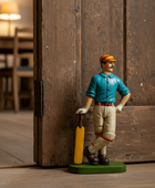 Figurine of a cricket player holding a bat against a wooden background