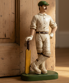 Statue of a cricketer holding a bat against a wooden background