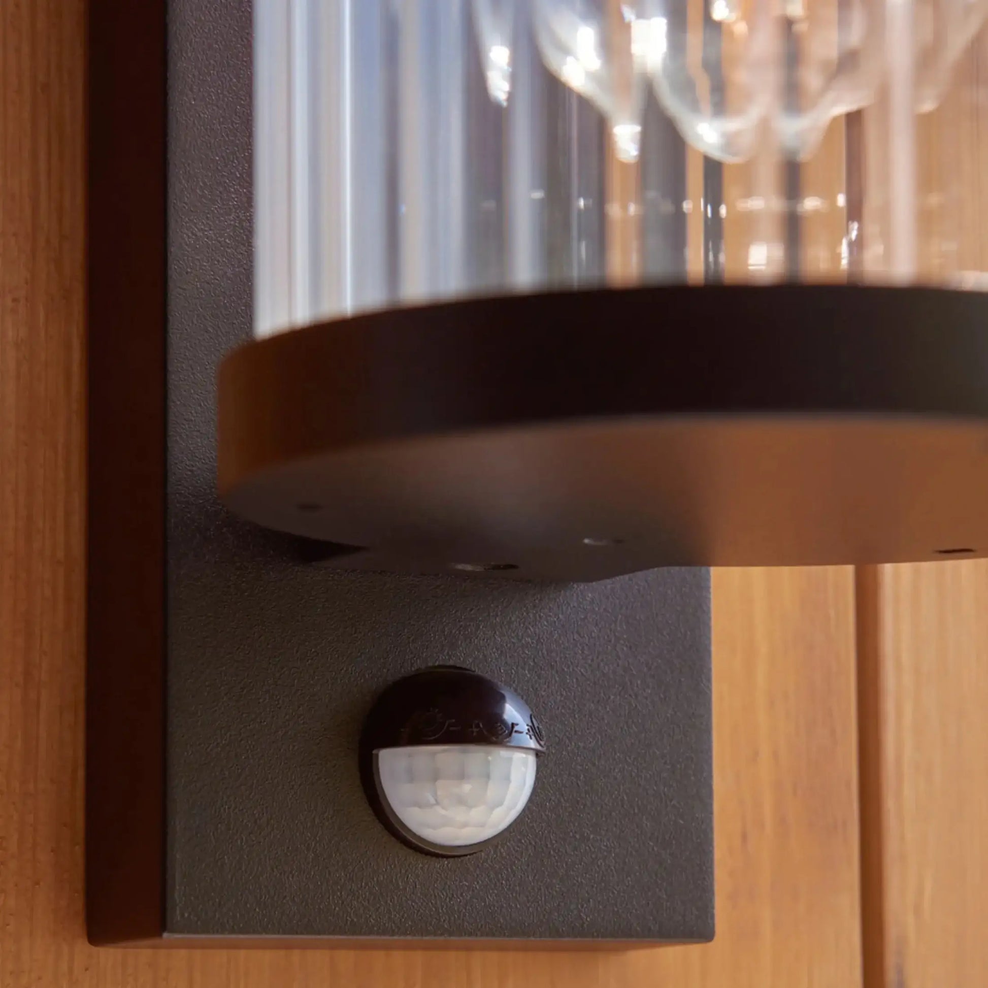 Motion sensor attached to a wall with a glass cover