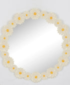 Round mirror with a floral frame of white flowers and yellow centers on a light gray background