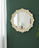 Decorative mirror with floral design on a green wall next to a plant