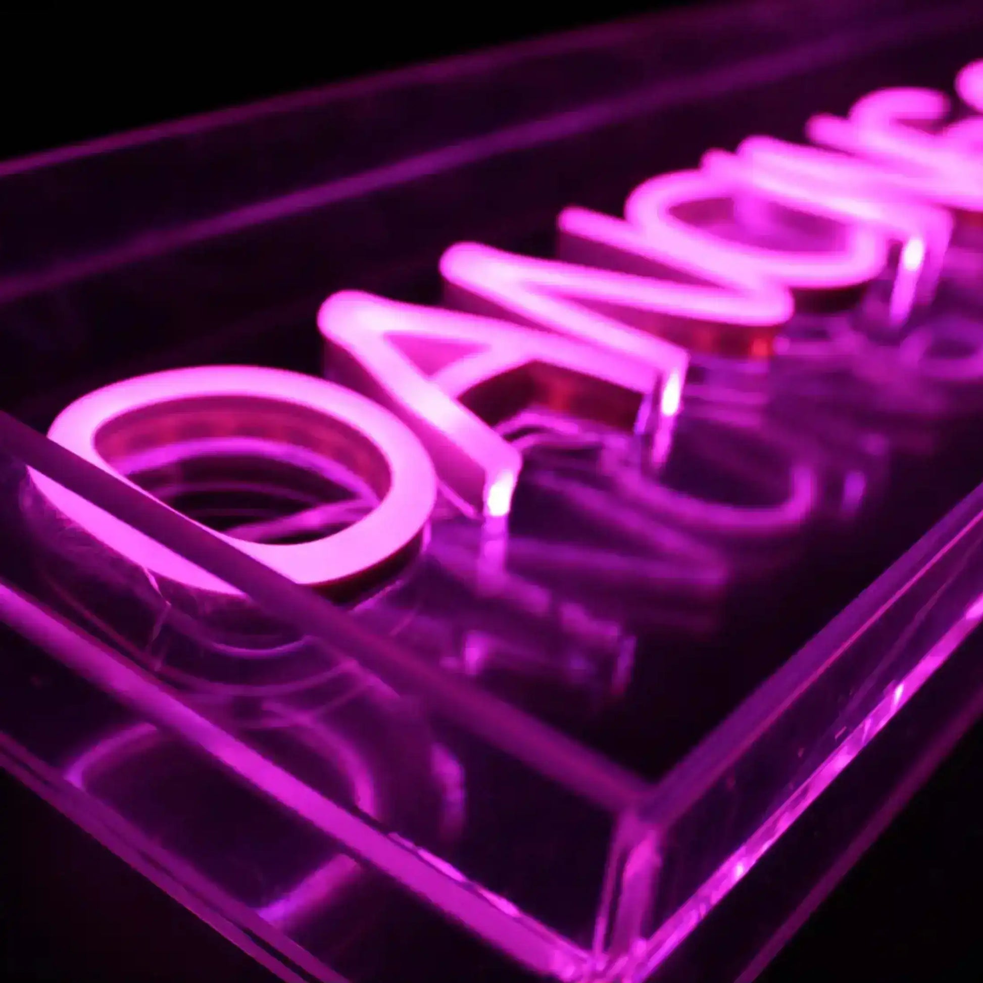 Neon sign with the word 'Dance' in pink on a black background