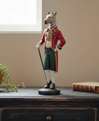 Statue of a zebra in a human-like outfit on a wooden surface with a plant and book in the background.