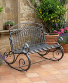 Wrought iron bench in a garden setting with potted plants and a stone wall.