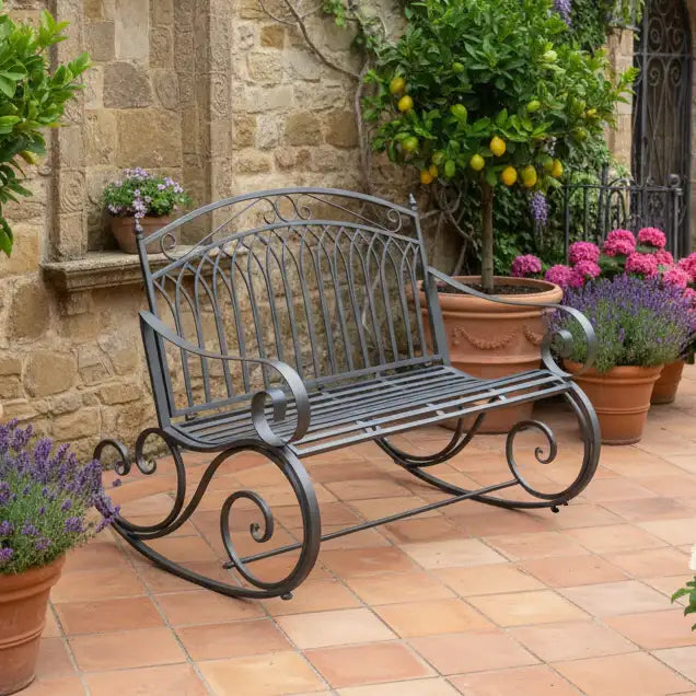 Wrought iron bench in a garden setting with potted plants and a stone wall.