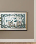 Framed vintage-style 'London Dry Gin' sign on a wall with a plant and window in the background.