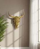 Decorative gold bull skull on a wall next to a window with sunlight streaming in