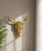 Decorative gold bull skull on a wall with a plant to the left
