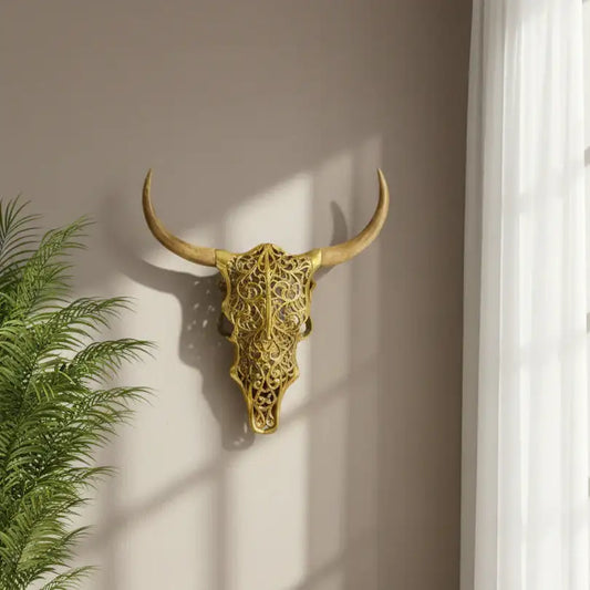 Decorative gold bull skull on a wall with a plant to the left