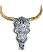 Decorative bull skull with intricate silver design and long horns on a white background