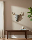 Living room with a wooden bench, decorative skull, and potted plant against a beige wall.