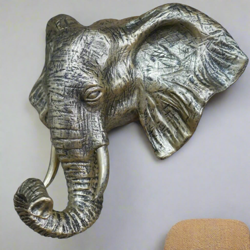 Bronze elephant head sculpture on a stone wall