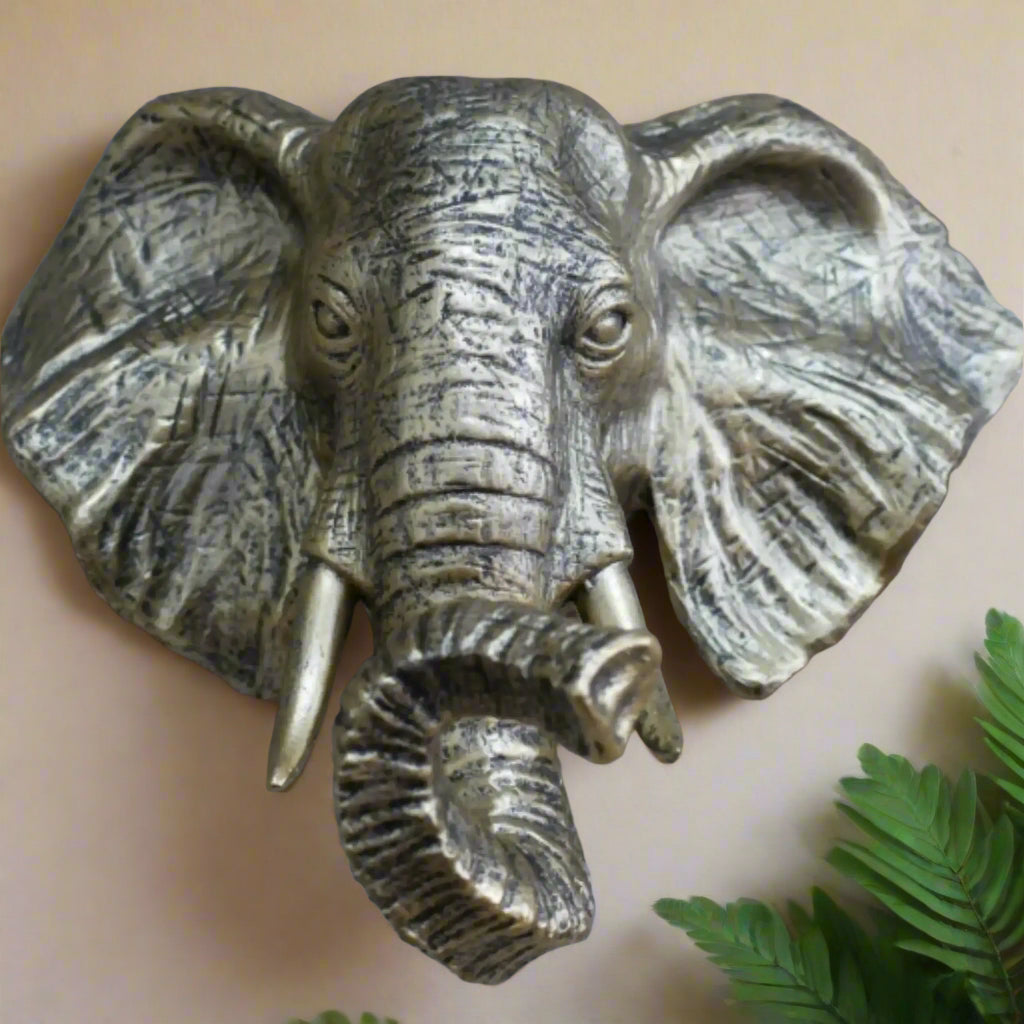 Bronze elephant head sculpture on a stone wall
