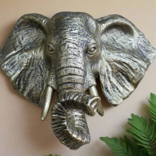 Bronze elephant head sculpture on a stone wall