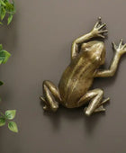 Bronze frog sculpture on a brown background with green leaves