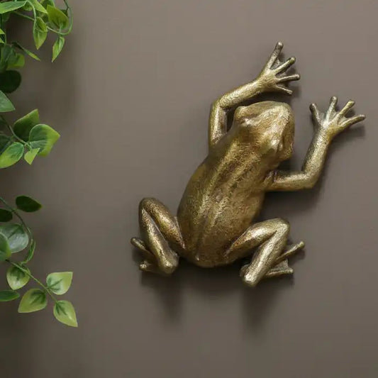 Bronze frog sculpture on a brown background with green leaves