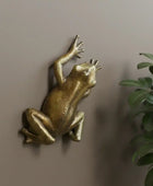 Gold frog sculpture on a textured stone wall