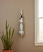 Wall-mounted model of a rocket with space-themed decor including NASA patches and astronaut figurines.