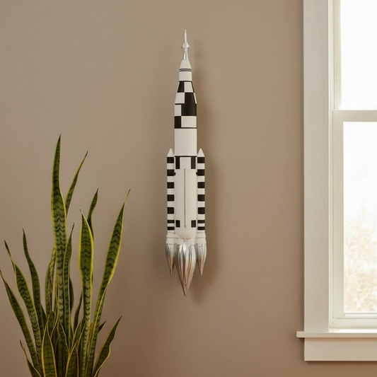 Decorative wall art resembling a rocket on a beige wall with a plant and window in the foreground.