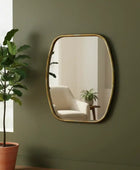 Gold-framed mirror on a green wall with a plant to the left