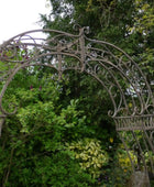 Decorative metal archway in a garden setting with greenery