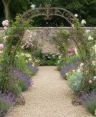 Wrought iron archway in a garden with flowers and a stone path