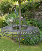 Decorative metal stand in a garden setting with flowers and a stone wall.