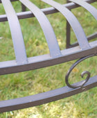 Metal garden bench with decorative armrest on a grassy background